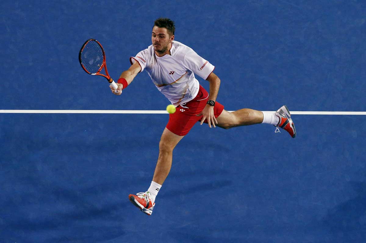 Stanislas Wawrinka of Switzerland hits a return to Novak Djokovic of