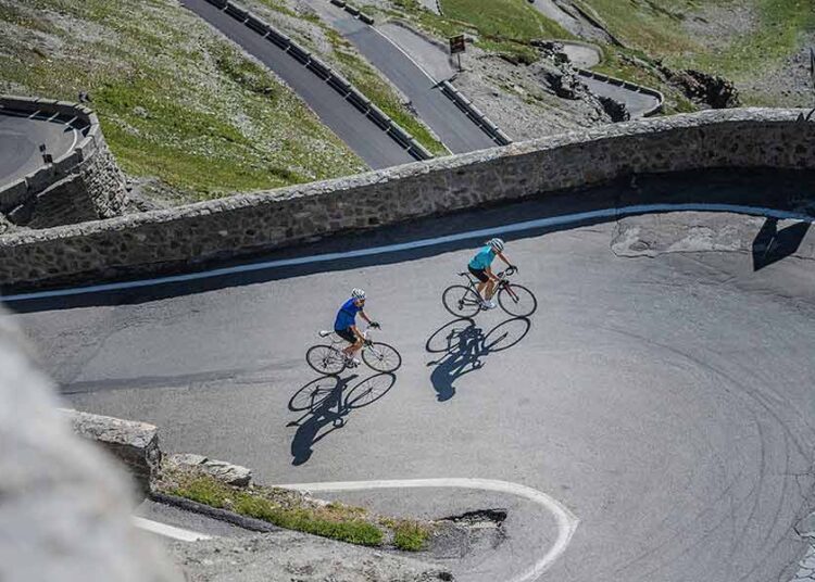 Stelvio, biker couple climbing - alpine pass for cyclists